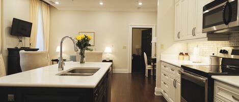 A modern kitchen with white cabinets, stainless steel appliances, and a central island with a sink.