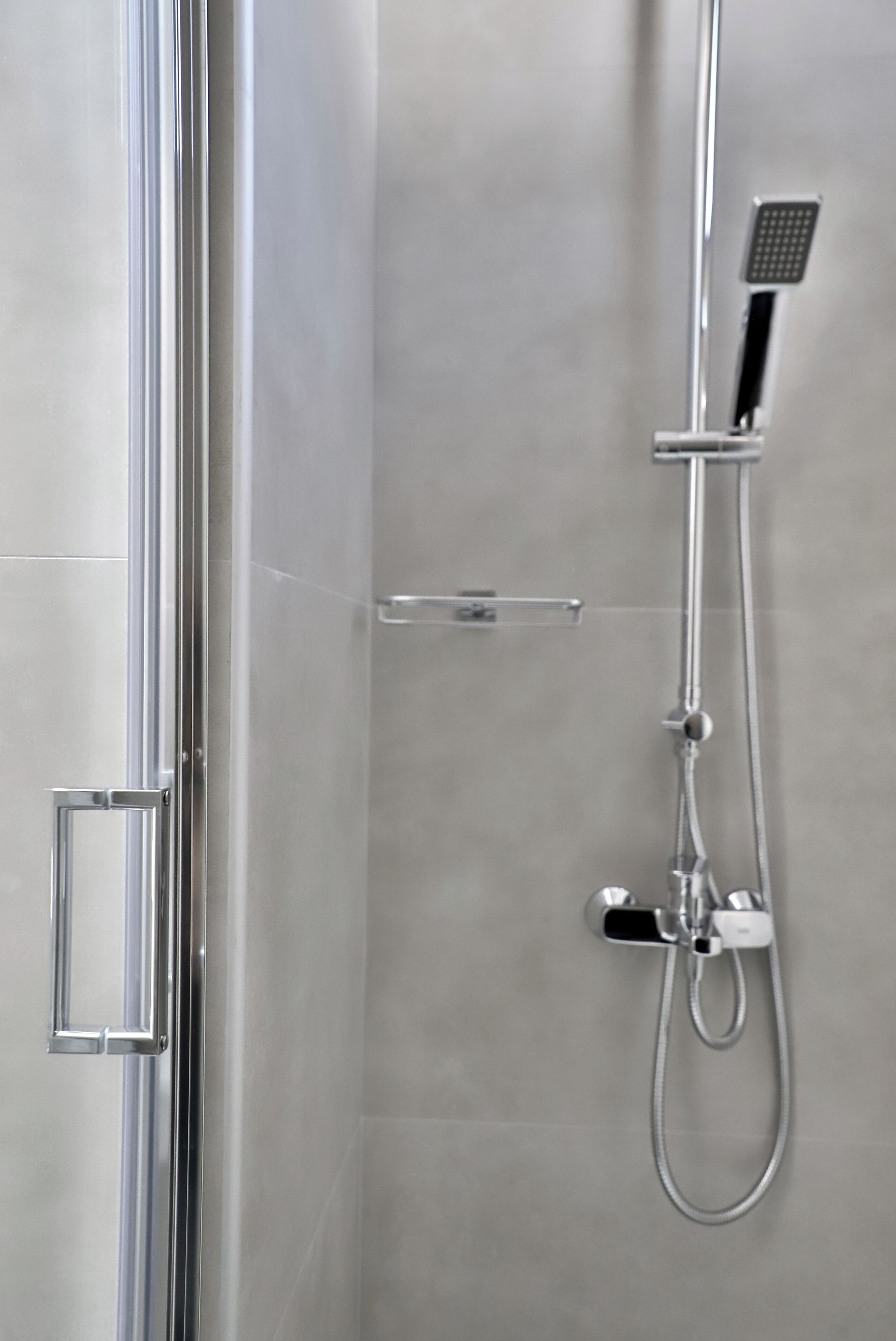 Une douche moderne dotée d’un pommeau de douche à main et d’un robinet mural.