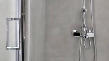 Une douche moderne dotée d’un pommeau de douche à main et d’un robinet mural.