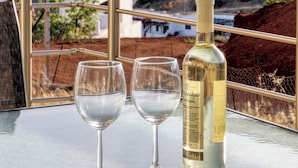 Een tafel met twee wijnglazen en een fles wijn, voor een achtergrond van een kuststadsbeeld.