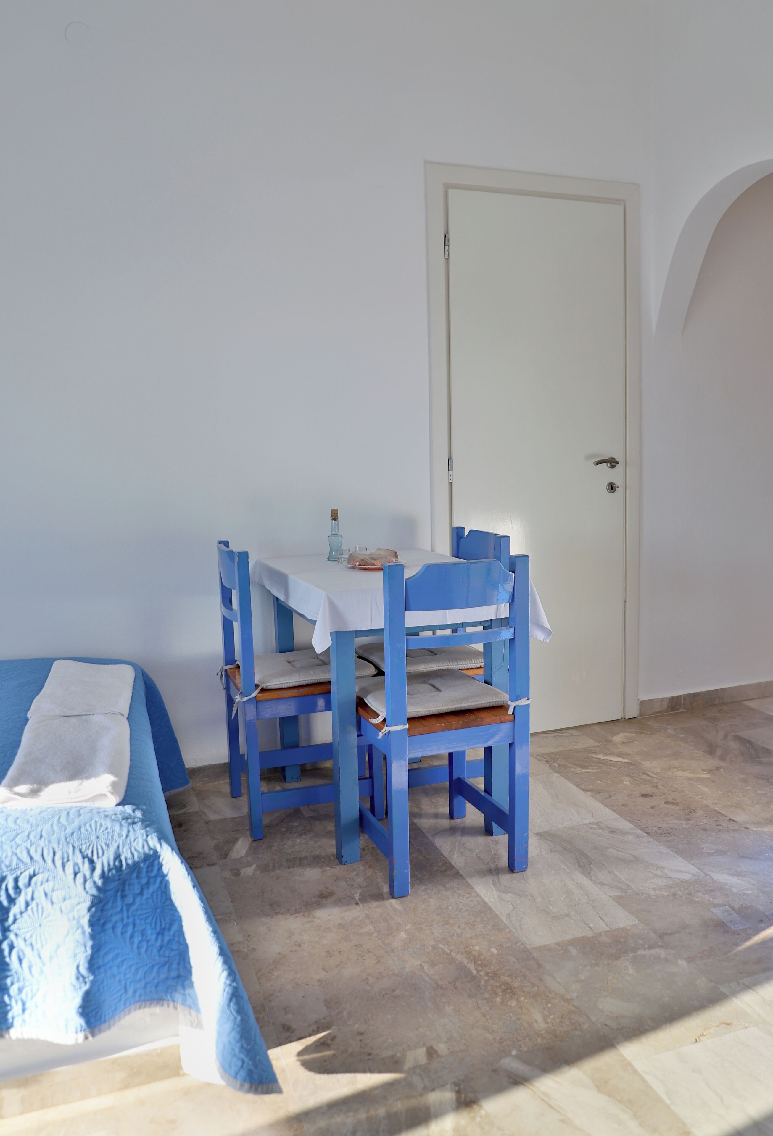 Een kamer met een bed, een tafel met stoelen en een deur.