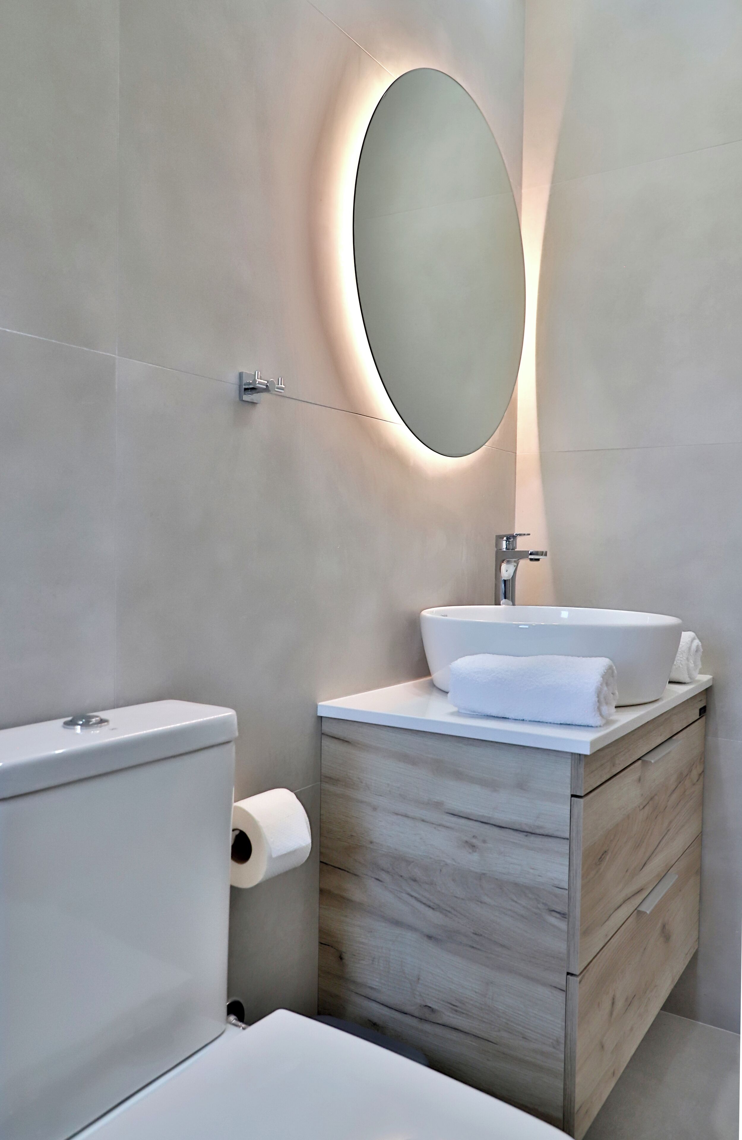 Un baño moderno con inodoro, lavamanos y espejo.