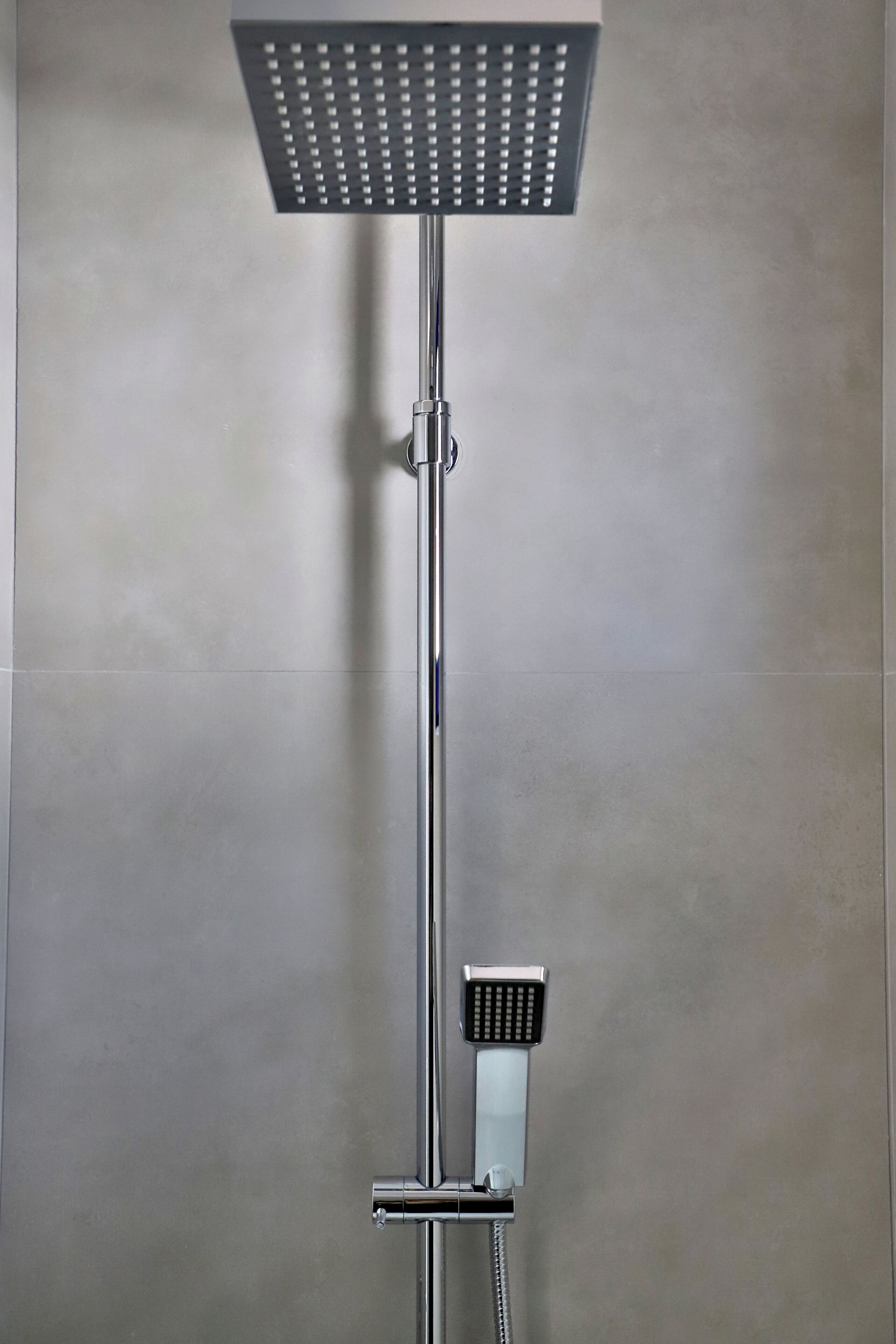 Eine moderne Dusche mit Duschkopf und Handbrause.