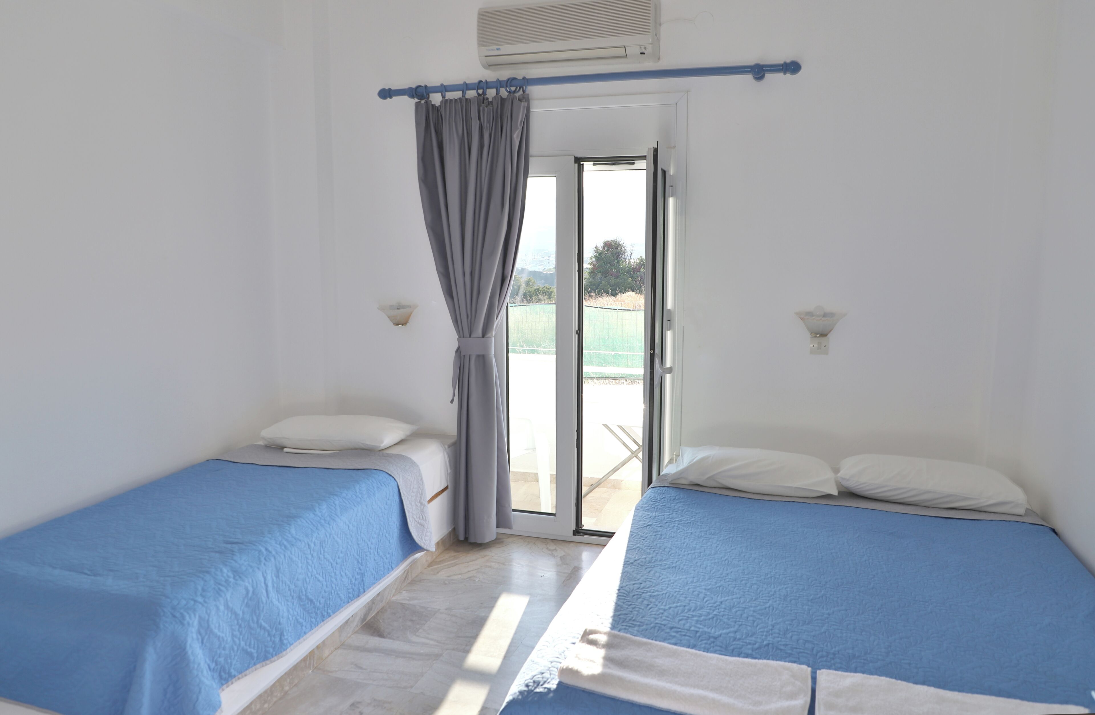 Una stanza con due letti, una porta scorrevole in vetro e un ventilatore a soffitto.