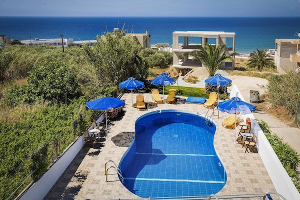 Una piscina al aire libre, sombrillas, sillones reclinables de piscina