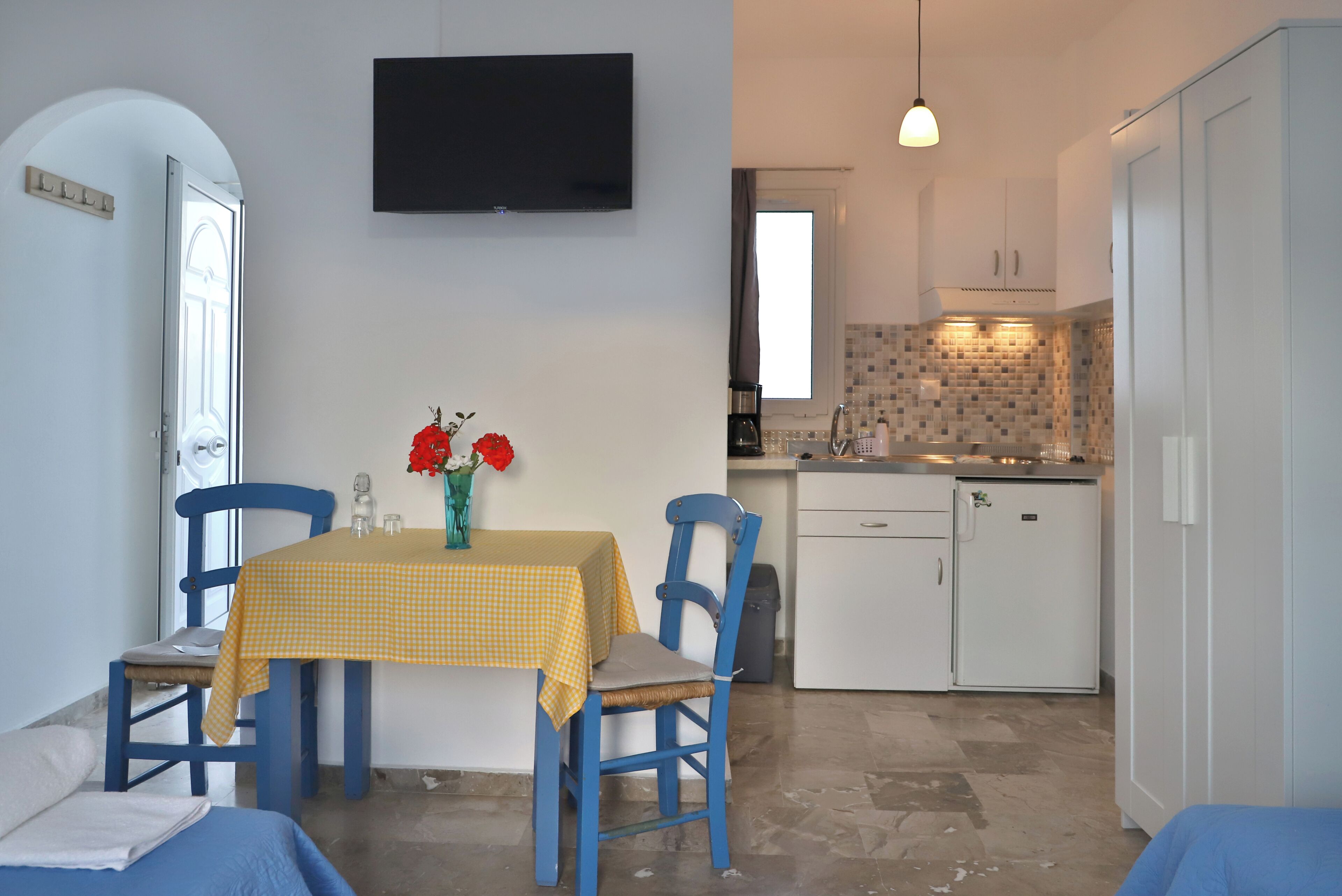 Una cocina compacta con armarios blancos, un refrigerador pequeño y salpicadero de azulejos.