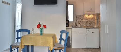Una cocina compacta con armarios blancos, un refrigerador pequeño y salpicadero de azulejos.
