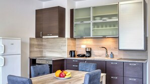 Een moderne keuken met een houten eettafel, grijze gestoffeerde stoelen en een fruitschaal.