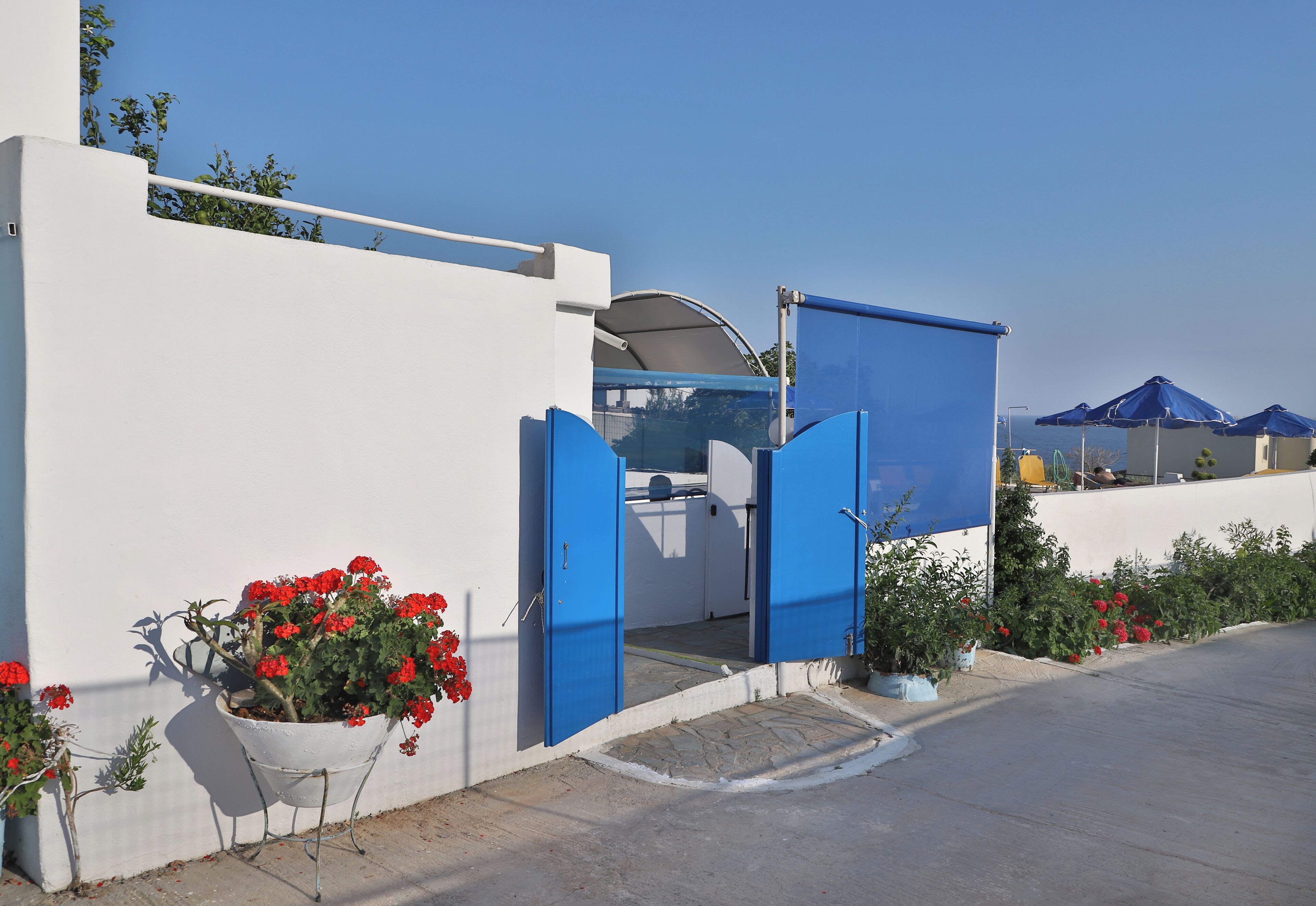 Un edificio blanco con puertas azules y macetas de flores rojas.