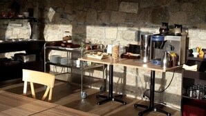 A rustic kitchen with a stone wall, wooden furniture, and various kitchen appliances.