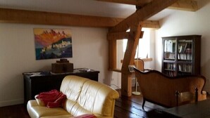A living room with a sofa, a bookshelf, and a painting on the wall.