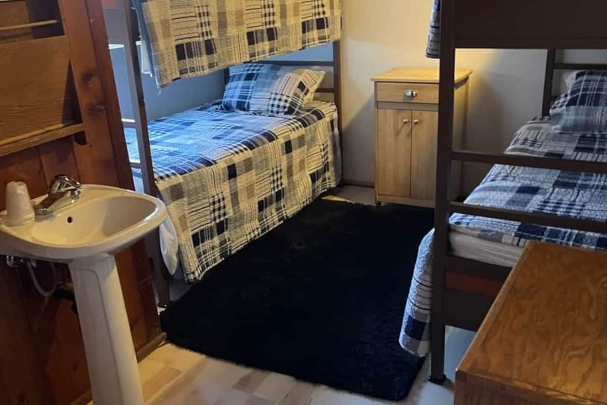 A compact room with bunk beds, a sink, and a small cabinet.