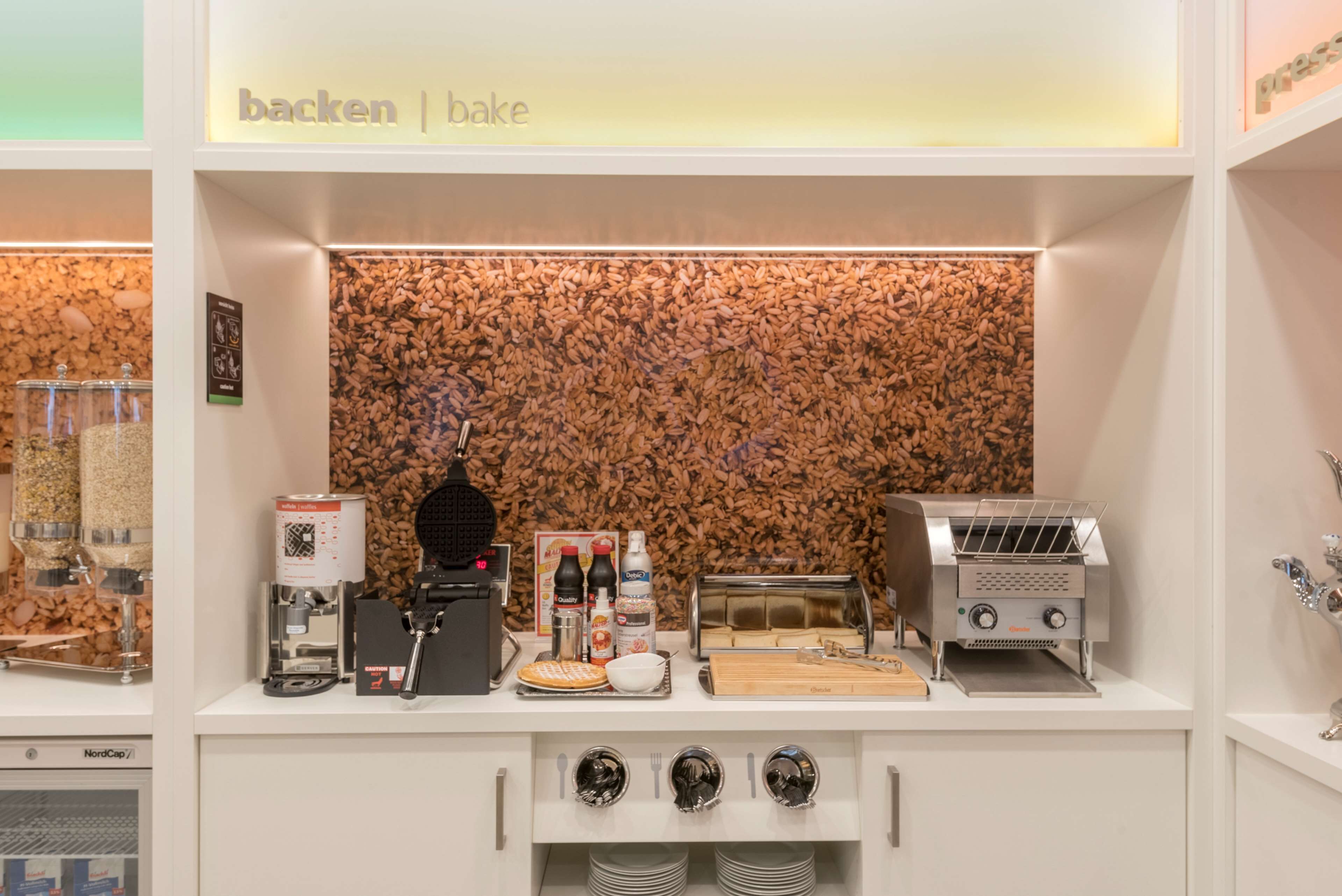 A kitchenette with a coffee machine, toaster, and a variety of condiments.