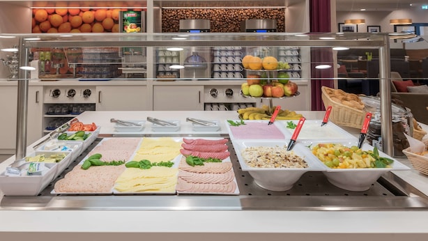 Un bufé con diversas opciones de comida, incluyendo frutas, verduras y platos ya preparados.