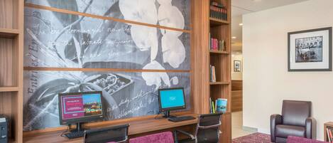 Una sala de conferencias con dos monitores de ordenador, un amplio mural floral y una estantería.