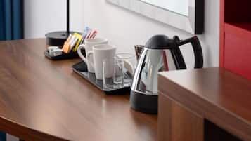 A wooden table with a tray holding a coffee maker, two white mugs, and two glasses.