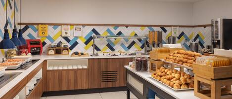 A breakfast buffet with various food items, a coffee machine, and a microwave.