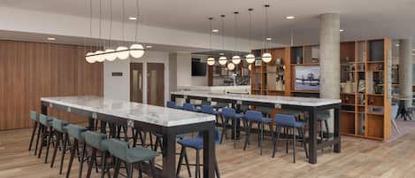Cocina moderna con encimeras de mármol, asientos de bar e iluminación colgante.
