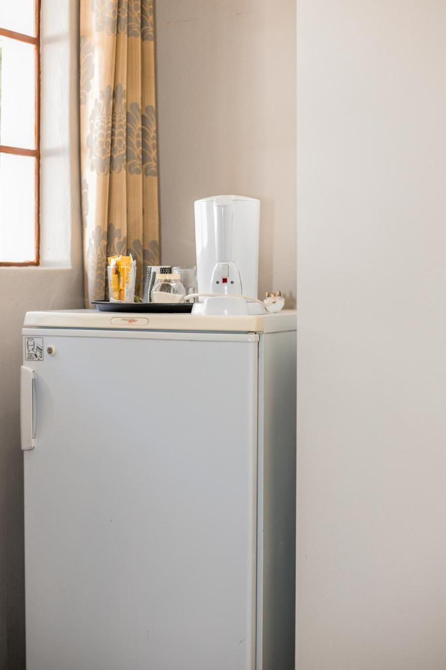 A compact, white refrigerator with a small freezer section on the left, a control panel, and a water dispenser on top.
