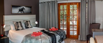 Una habitación de hotel con una cama grande, un escritorio y vistas a través de un ventanal.