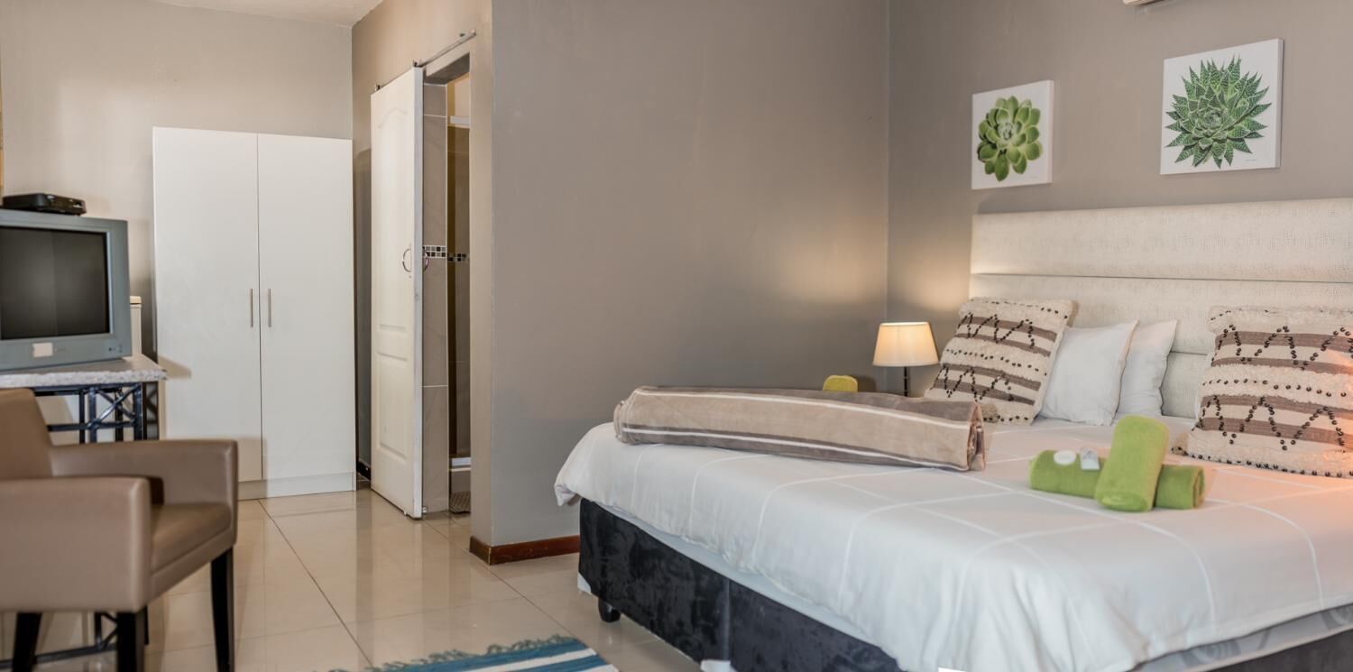 Una habitación de hotel con cama, televisor, escritorio y armario.