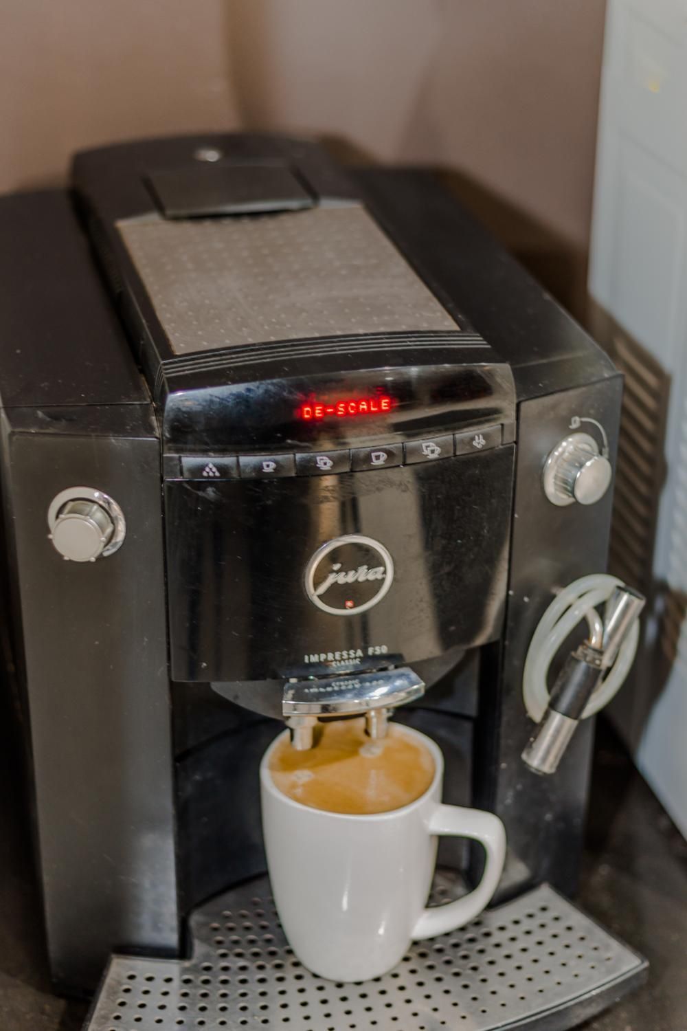 Una máquina de café con pantalla digital sirviendo café en una taza.