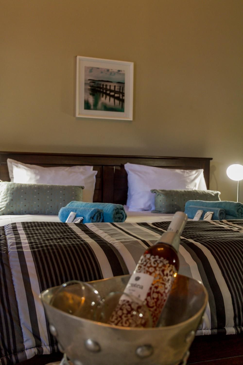 Ein Hotelzimmer mit Bett, Kissen, einer Nachttischlampe und einem gerahmten Bild an der Wand.