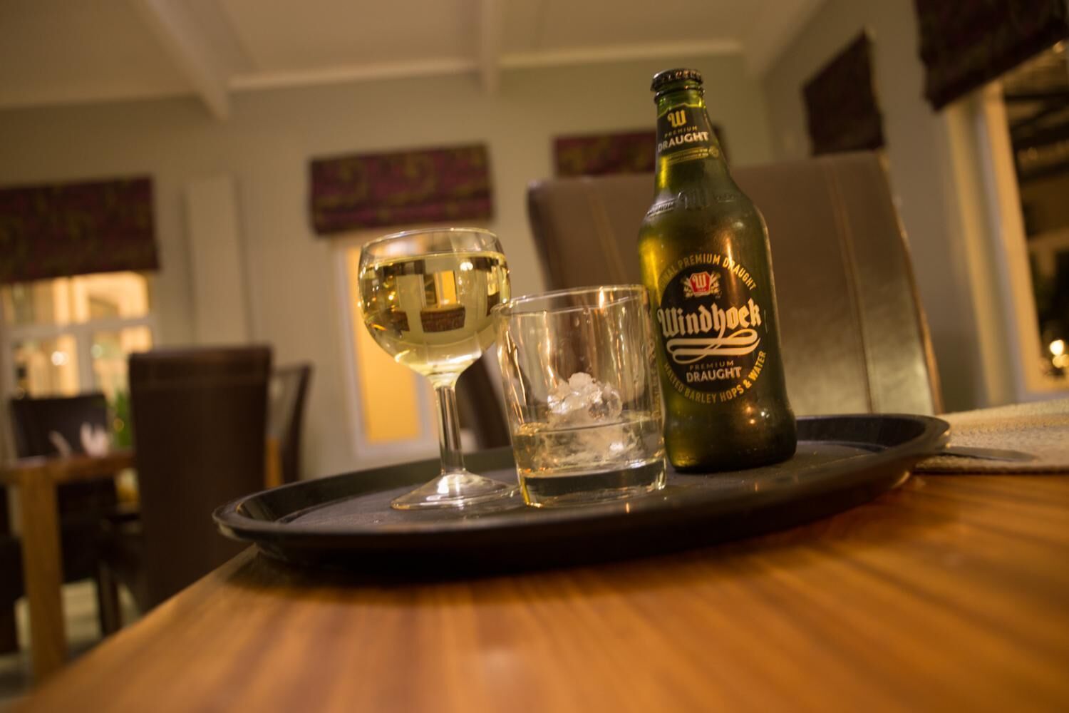 Une bouteille de bière Windhoek Premium Draught et un verre de vin blanc sur un plateau.