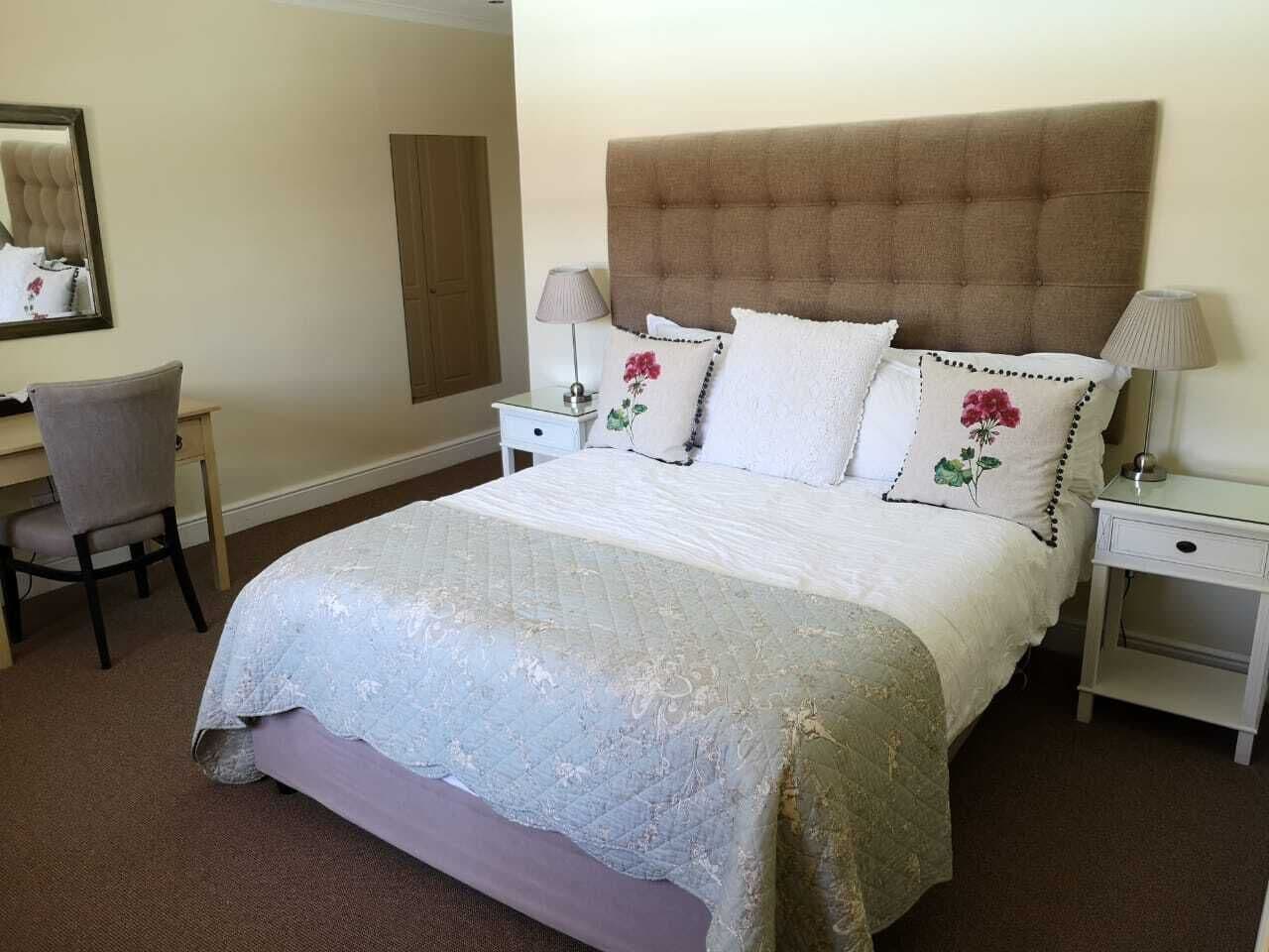 Una camera d'albergo ben ordinata con un letto grande, due comodini, una sedia e una scrivania.