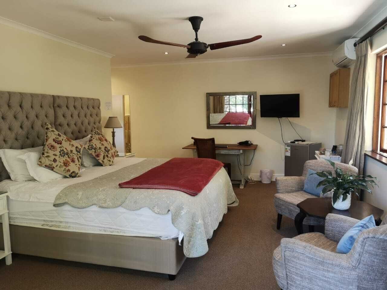 Una habitación de hotel con cama, escritorio, silla, televisor y ventilador de techo.