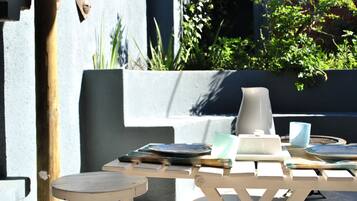 A patio area with a table set for dining, a bench, and a potted plant.