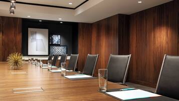 A conference room with a long wooden table, black chairs, and a decorative golden sphere.