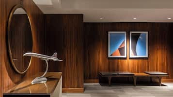 A modern lobby with a wooden wall, a round mirror, a bench, and two framed artworks.