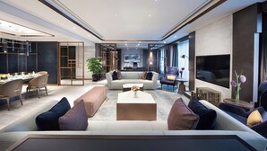 Una sala de estar moderna con un conjunto de sofá, una mesa de centro y un televisor. Hay un comedor con sillas y una mesa.