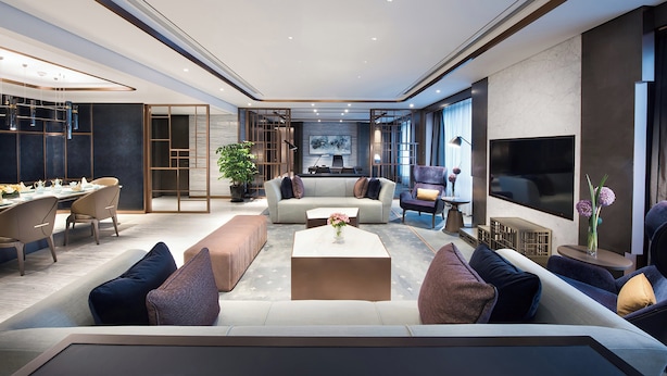 A modern living room with a sofa set, coffee table, and a TV. There is a dining area with chairs and a table. - Crowne Plaza Shanghai Pujiang by IHG (Shanghai)