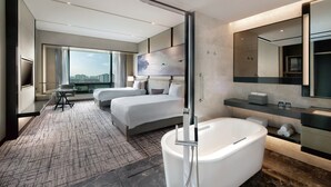 A modern hotel room with two beds, a large window with a city view, a flat-screen TV, a desk, and a large bathtub. - Crowne Plaza Shanghai Pujiang by IHG (Shanghai)