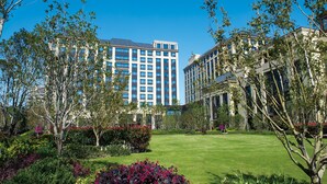 Un hotel con un edificio grande, un césped bien cuidado y varios arbustos.