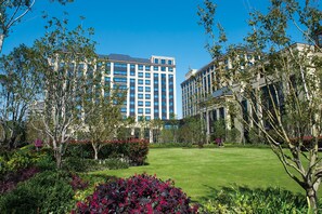 Un hotel con un edificio grande, un césped bien cuidado y varios arbustos.