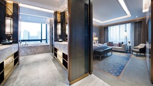 A modern hotel room with a large window, a sitting area with a sofa and armchairs, a small table, and a large mirror. - Crowne Plaza Shanghai Pujiang by IHG (Shanghai)