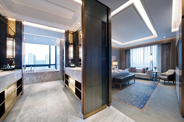 A modern hotel room with a large window, a sitting area with a sofa and armchairs, a small table, and a large mirror. - Crowne Plaza Shanghai Pujiang by IHG (Shanghai)
