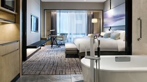 A modern hotel room with a large bed, a desk, a chair, a bathroom with a bathtub, and a large window with curtains. - Crowne Plaza Shanghai Pujiang by IHG (Shanghai)