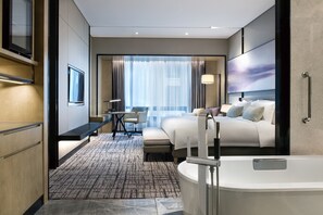 A modern hotel room with a large bed, a desk, a chair, a bathroom with a bathtub, and a large window with curtains. - Crowne Plaza Shanghai Pujiang by IHG (Shanghai)