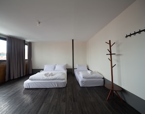 Habitación de hotel con dos camas, perchero y vista a la ciudad.