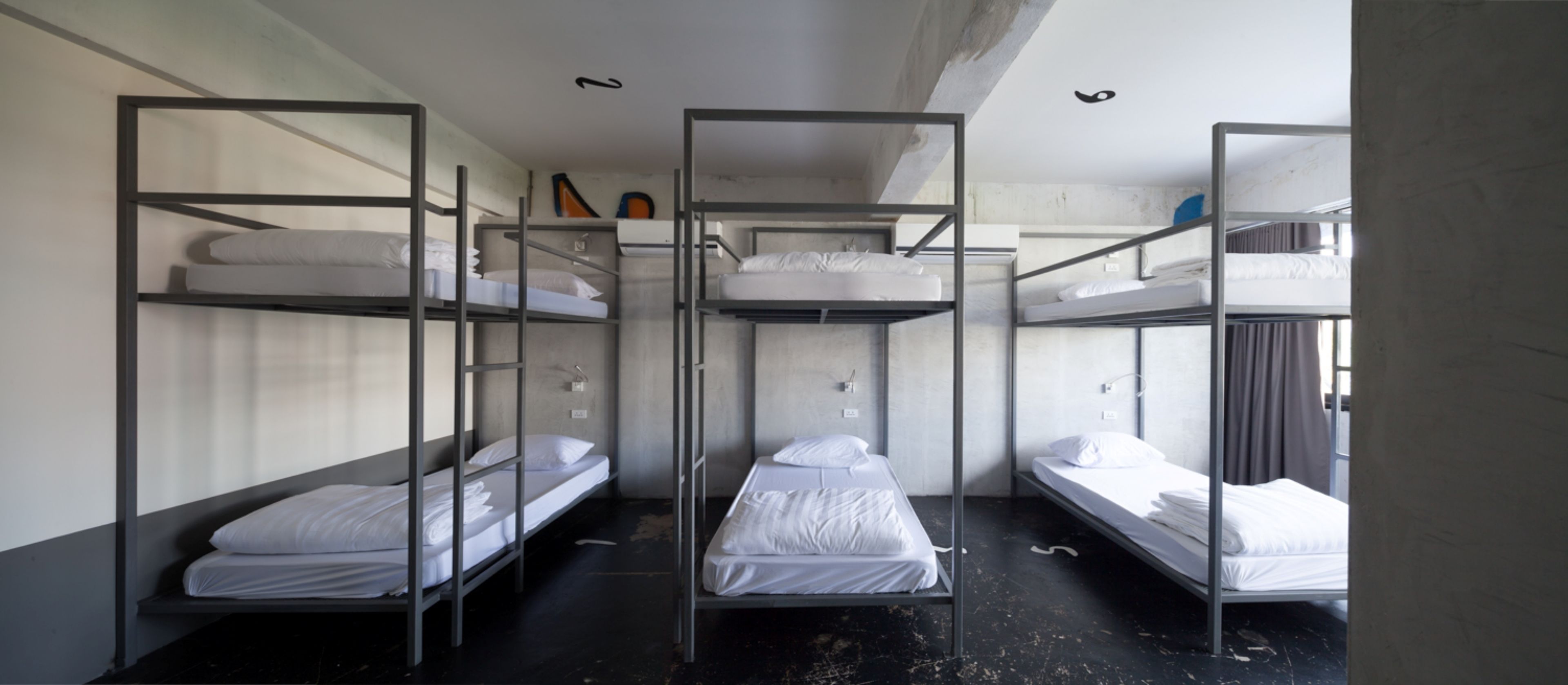 Un dormitorio con literas, suelo de hormigón y un diseño sencillo y funcional.