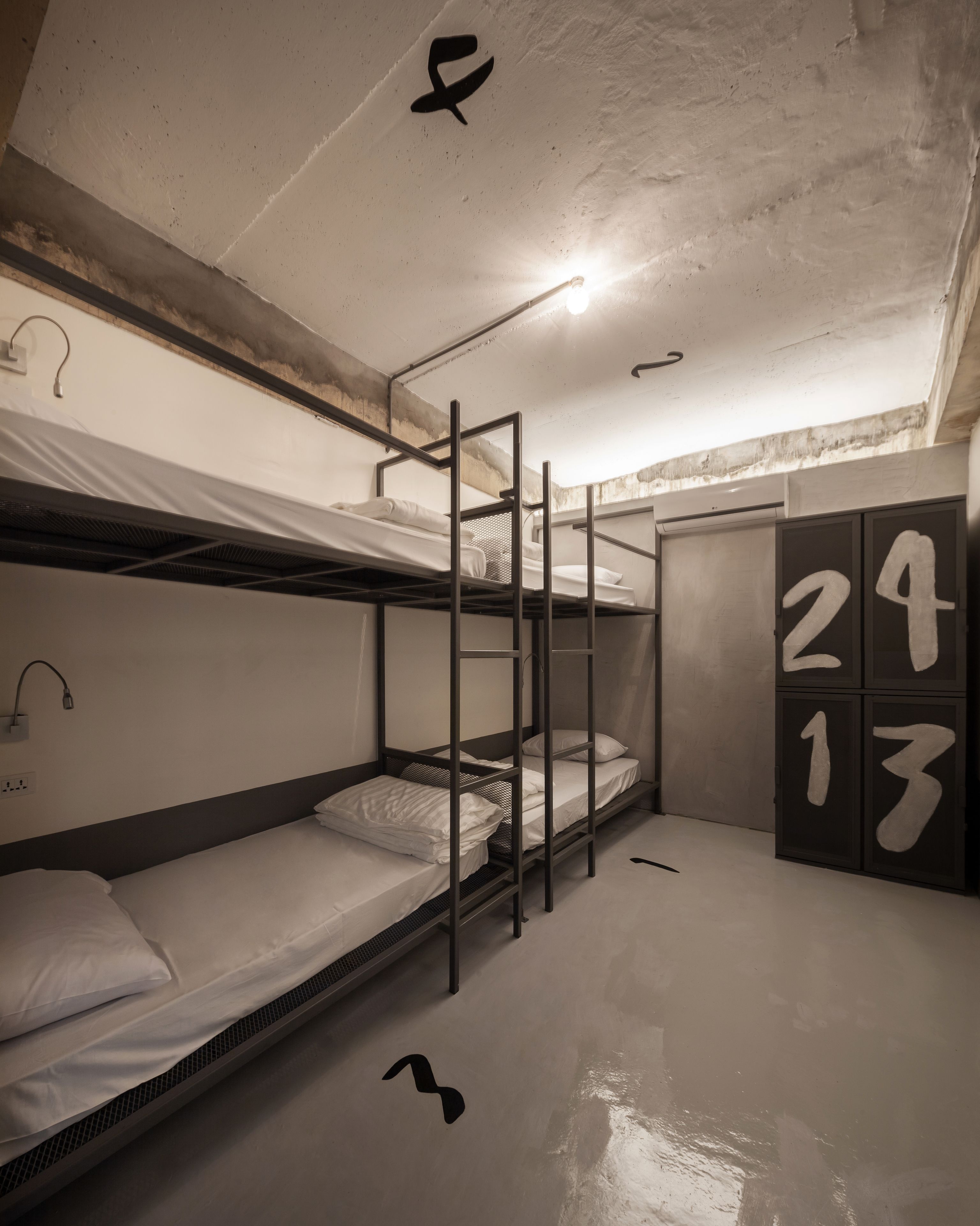 Un dormitorio con literas, un armario con números y una lámpara en el techo.