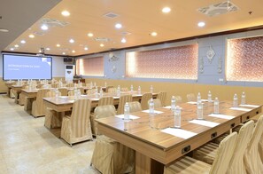 A conference room with multiple tables, chairs, and a projector screen displaying a presentation. - Jinsa Lakeside View Hotel (Jinsha)