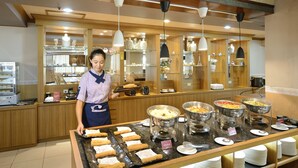 A buffet setup with various food items and a staff member serving. - Jinsa Lakeside View Hotel (Jinsha)