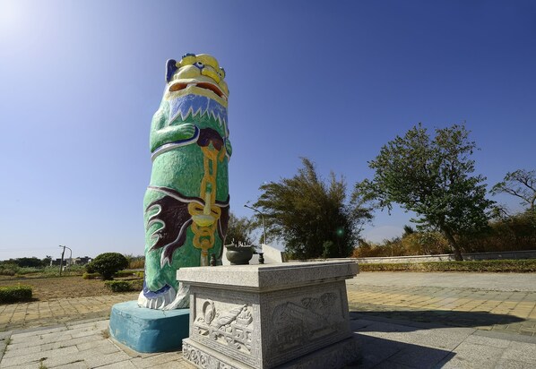 A large, colorful statue on a pedestal in an open area with trees and a clear sky. - Jinsa Lakeside View Hotel (Jinsha)