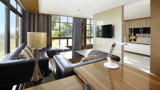 A modern hotel room with a large window, a sofa, a dining table, and a TV. - Jinsa Lakeside View Hotel (Jinsha)
