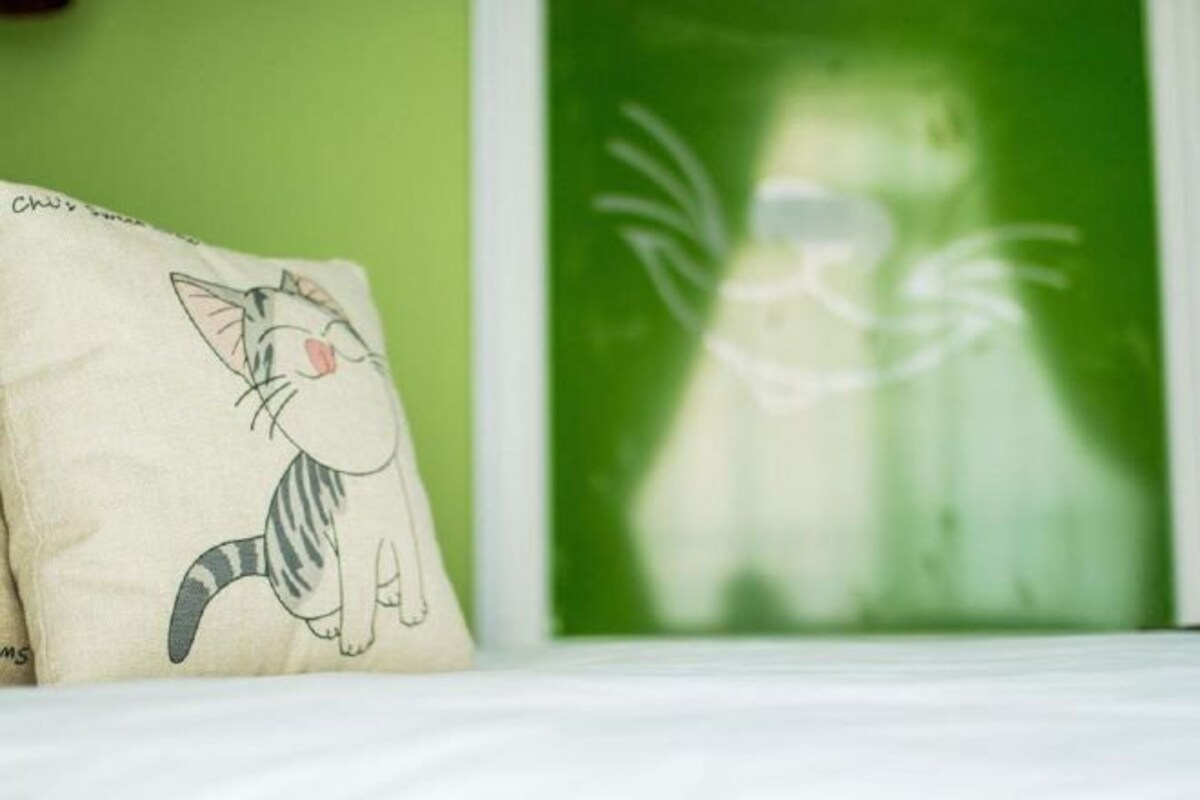 A pillow with a cat design on a bed.